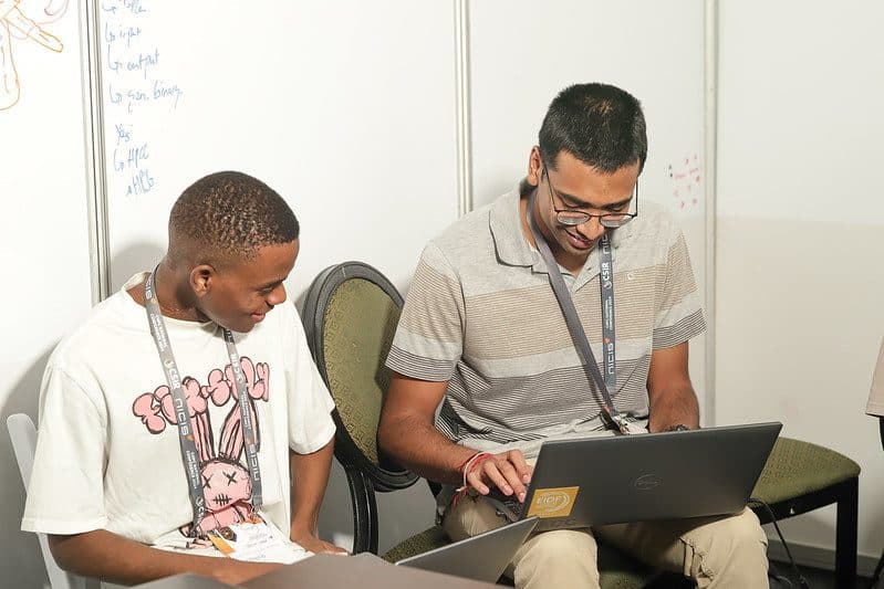 Two members of the Wits A team working together at a laptop in their booth