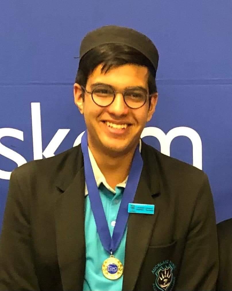 Talhah Patelia wearing a gold medal in front of an Eskom Expo banner