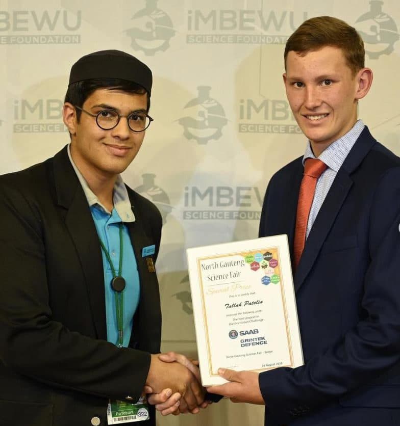 Talhah Patelia shaking hands with a presenter while holding his special prize certificate