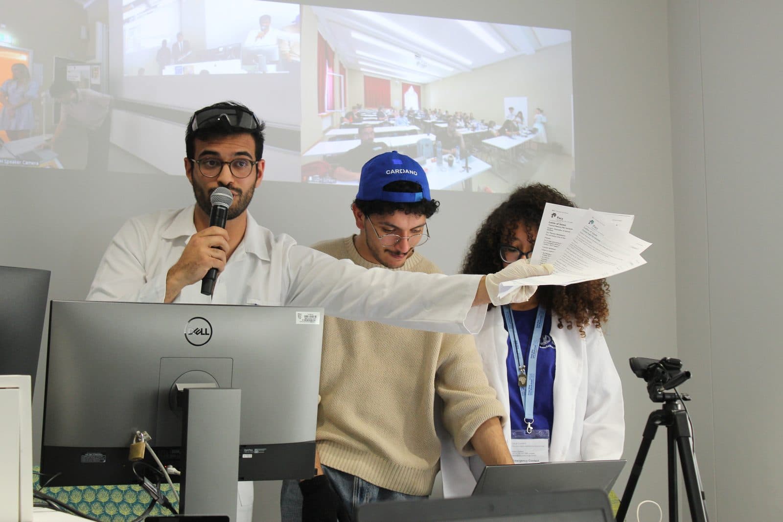 Talhah Patelia speaking into a microphone while presenting the final project with two teammates